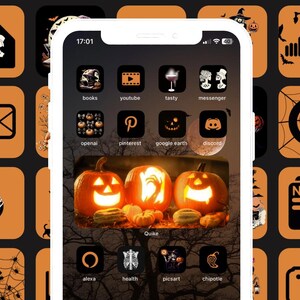May include: A screenshot of an iPhone with a Halloween-themed home screen. The icons are black and white with orange backgrounds. The icons include apps like YouTube, Pinterest, Google Earth, Discord, Alexa, Health, Picsart, and Chipotle. The background image is a close-up of three jack-o'-lanterns.