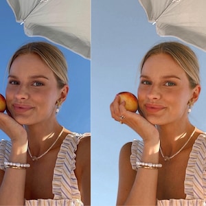 May include: A woman with blonde hair is holding a peach in her hand. She is wearing a striped top and a pearl necklace. She is smiling at the camera.