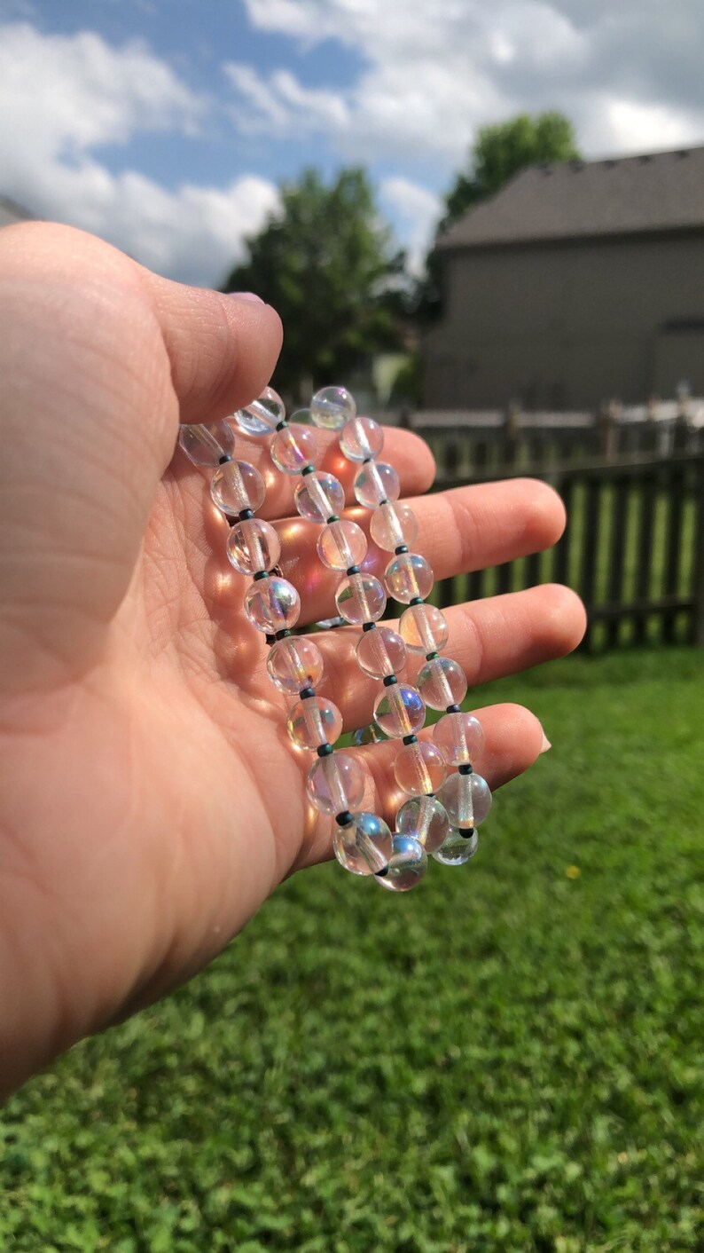 May include: A strand of iridescent clear glass beads with black string.