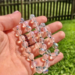 May include: A white iridescent crystal beaded necklace with dark blue beads between each crystal bead.