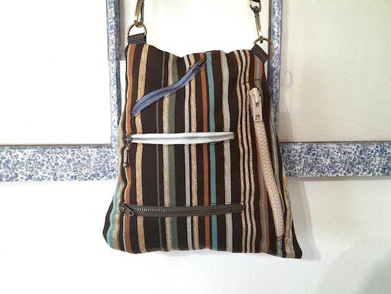 A handmade striped canvas crossbody with actual zippered pockets — the kind of bag a person spots and immediately asks 'where did you get that?'