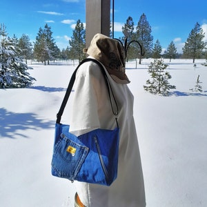 An image taken outdoors with snow in the background.  The purse is worn by a manikin in a white blouse.
