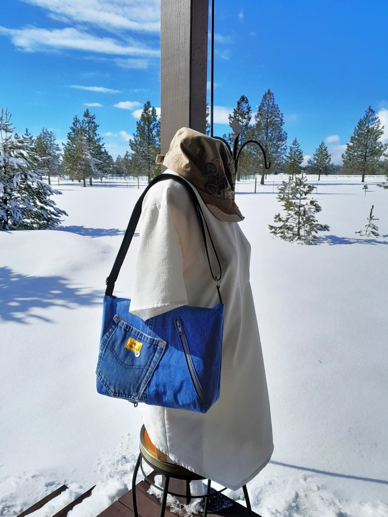 An image taken outdoors with snow in the background.  The purse is worn by a manikin in a white blouse.