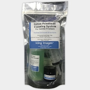 May include: A clear plastic bag containing a Canon Printhead Cleaning System for edible printers. The kit includes a green bottle of non-toxic printhead cleaner, a black jar of black seal sealing ink, and a clear plastic syringe.