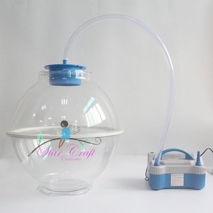 May include: A clear plastic sphere with a white rim and a blue air pump. The sphere has a clear plastic tube attached to the top and a small blue air valve. The air pump is connected to the tube with a clear plastic hose. The sphere is sitting on a white surface. The text "Star Craft Creations" is printed on the sphere.