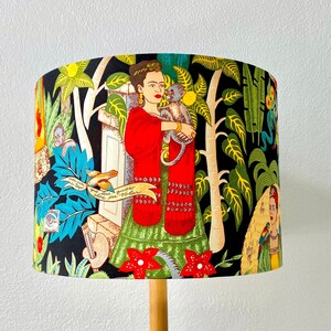 May include: A black lampshade with a colourful design featuring a woman with a monkey, flowers, and the text "Good Luck, All That You Desire".