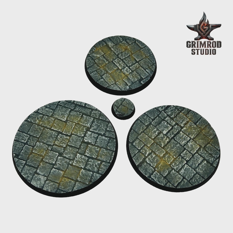 May include: A set of four circular bases with a cobblestone texture, in varying sizes. The bases are primarily gray with yellow highlights, suggesting an aged or weathered appearance. The Grimrod Studio logo is in the upper right corner.