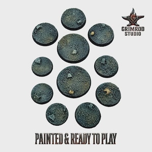 Peut inclure: Un ensemble de onze socles miniatures ronds peints, avec un aspect de terre craquelée texturée. Les socles sont de différentes tailles et présentent de petits rochers et débris. Le texte "PAINTED & READY TO PLAY" est en bas, avec le logo Grimrod Studio en haut à droite.
