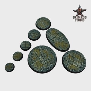 May include: A collection of gray stone bases in various shapes and sizes, including circles and an oval. The bases feature a cobblestone texture with yellow-green accents. The Grimrod Studio logo is in the upper right corner.