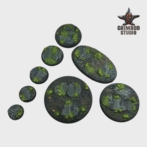 May include: A collection of miniature terrain bases in various shapes and sizes. The bases feature a textured, dark gray surface with patches of green moss and rock formations. The Grimrod Studio logo is in the upper right corner.