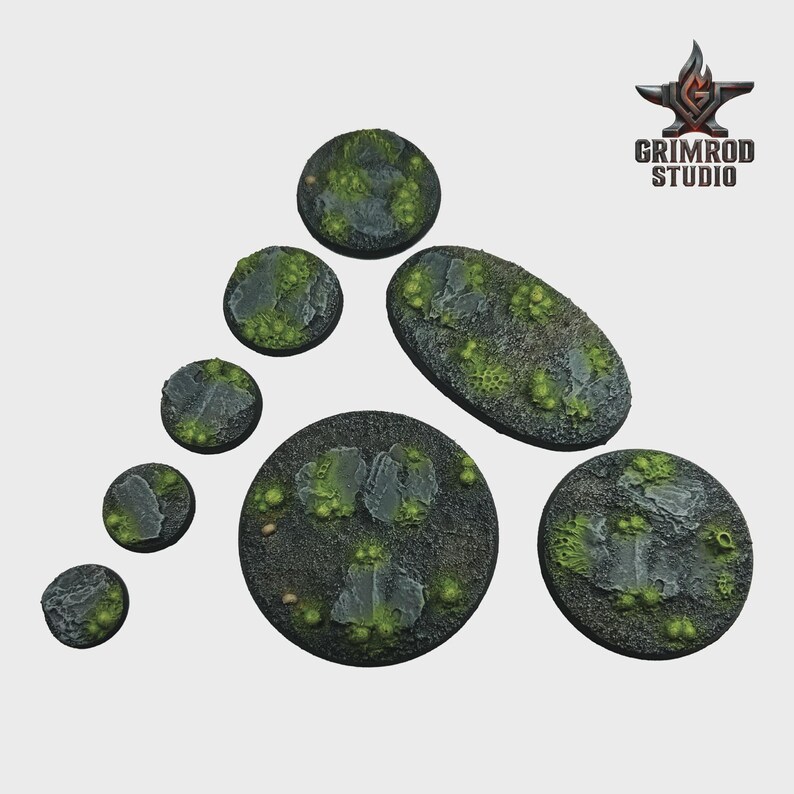 May include: A collection of miniature terrain bases in various shapes and sizes. The bases feature a textured, dark gray surface with patches of green moss and rock formations. The Grimrod Studio logo is in the upper right corner.