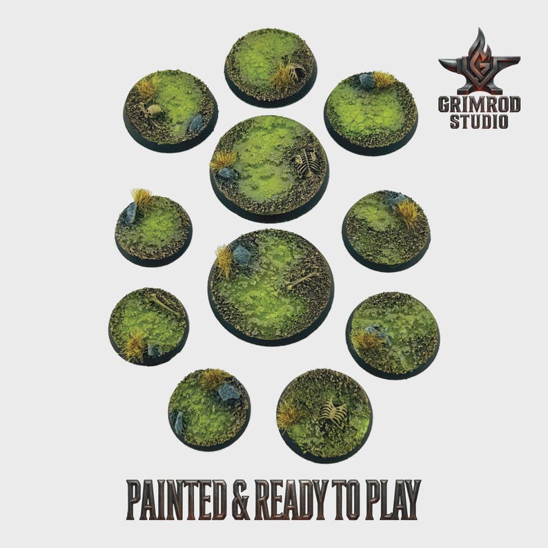 May include: A collection of painted miniature bases, round and varying in size. The bases feature a green, grassy texture with small rocks, dried grass, and bone details. The text "PAINTED & READY TO PLAY" is displayed at the bottom.
