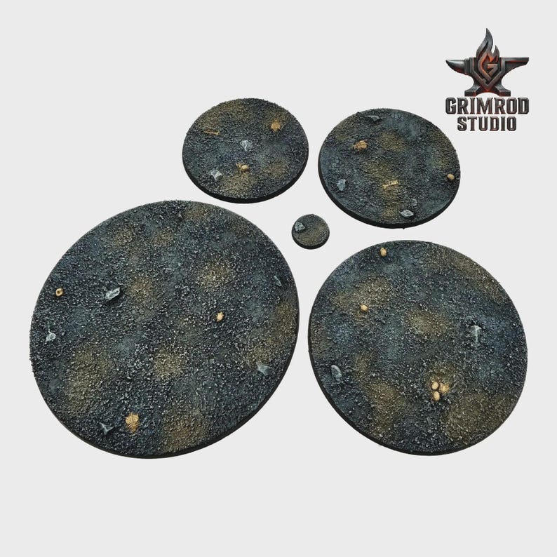 May include: A collection of textured, circular bases in varying sizes, designed for miniature figures. The bases are primarily dark gray with brown and tan accents, and small rock-like details. The Grimrod Studio logo is visible in the upper right corner.