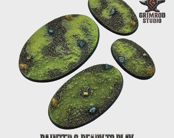 May include: Four oval-shaped miniature bases with a textured, grassy terrain. The bases are painted with green, brown, and tan colors, and small rocks are visible. The text "PAINTED & READY TO PLAY" is at the bottom. The Grimrod Studio logo is in the upper right.