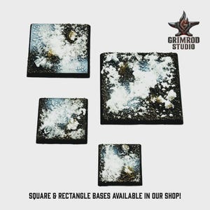 Op de afbeelding: Vier vierkante miniatuurbasen met een textuur, sneeuwachtig ontwerp. De basen zijn donkerbruin met witte en lichtblauwe accenten, en de tekst "SQUARE & RECTANGLE BASES AVAILABLE IN OUR SHOP!" staat onderaan.