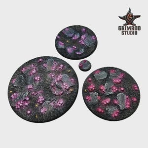 May include: A set of four circular bases with a textured, dark gray surface. The bases feature pink, purple, and gray organic-looking elements. The Grimrod Studio logo is in the upper right corner.
