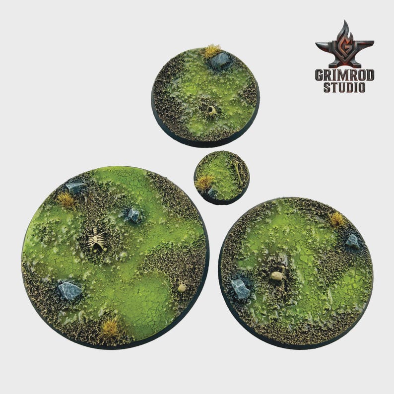 May include: Four circular miniature bases with a grassy, textured surface. The bases feature a green and brown color scheme, with small rocks, tufts of grass, and a skeleton. The Grimrod Studio logo is in the upper right corner.