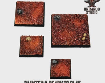 May include: Four square, textured bases with a reddish-brown color scheme, suitable for miniature figures. The bases have a cracked, rough appearance, with small details like rocks and other elements. The text "PAINTED & READY TO PLAY" is visible.