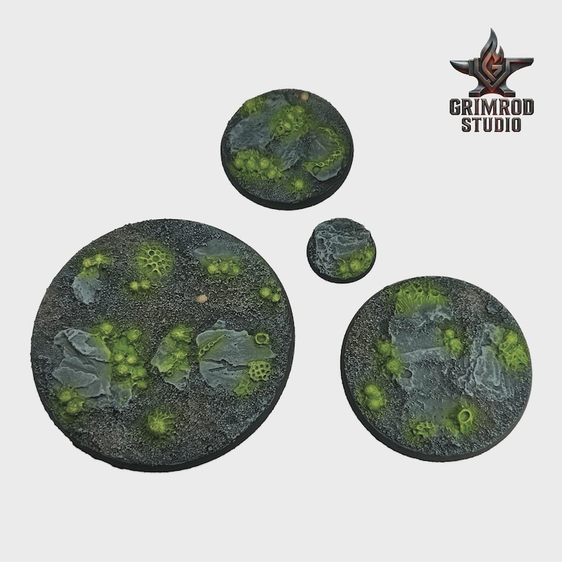 May include: Four circular miniature bases with a textured, rocky surface. The bases feature patches of green moss and small, light green plant-like details. The Grimrod Studio logo is in the upper right corner.