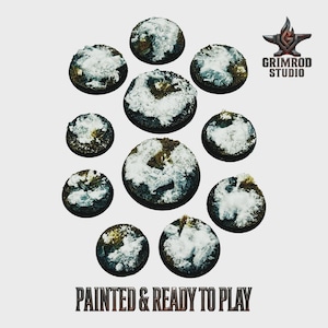 May include: A collection of eleven circular, miniature bases, painted with a snow-covered terrain effect. The bases vary in size and are arranged in a circular pattern. The text "PAINTED & READY TO PLAY" is at the bottom.