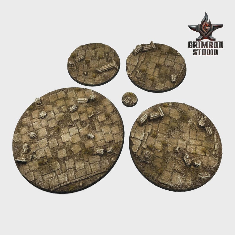 May include: A set of five circular miniature bases with a cobblestone texture and scattered architectural ruins. The bases vary in size, with the largest measuring approximately 3 inches in diameter. The bases are in shades of brown and gray.