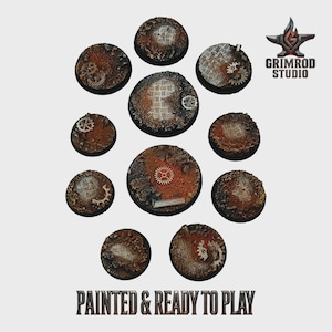 May include: Eleven circular bases with a steampunk design. The bases have a rusty brown and orange colour scheme, with embedded gears and metal plate details. The text "PAINTED & READY TO PLAY" is at the bottom.