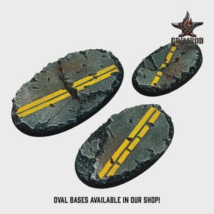 May include: Three oval-shaped miniature bases with a road design. The bases are gray with yellow road lines and a cracked asphalt texture. The bases are surrounded by a black border. The text "OVAL BASES AVAILABLE IN OUR SHOP!" is at the bottom.