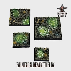 May include: Four square miniature bases with textured surfaces, featuring green and brown terrain with patches of grass and small rocks. The bases are painted and ready to play, as indicated by the text at the bottom of the image.