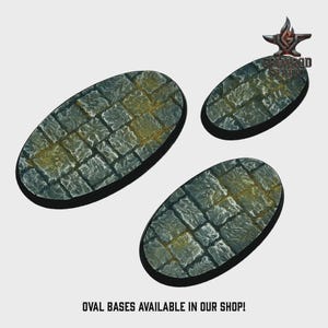 May include: Three oval-shaped bases with a cobblestone texture, painted in shades of gray and accented with yellow-brown hues. The bases are designed for miniature figures. Text at the bottom reads: OVAL BASES AVAILABLE IN OUR SHOP!