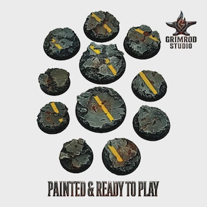 Peut inclure: Onze socles miniatures peints pour ressembler à des sections de route en asphalte. Ils sont gris avec des marquages routiers jaunes et texturés pour simuler l'usure. Le texte "PAINTED & READY TO PLAY" est en bas de l'image.