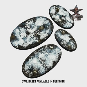 Op de afbeelding: Vier ovale bases met een getextureerd, met sneeuw bedekt uiterlijk. De bases zijn donkerbruin met witte en grijze accenten. De tekst "OVAL BASES AVAILABLE IN OUR SHOP!" staat onderaan. Het Grimrod Studio logo staat rechtsboven.