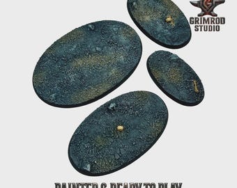 May include: Four oval-shaped bases with a textured, rocky surface in shades of blue, gray, and brown. The bases are painted and ready to play, as indicated by the text. The Grimrod Studio logo is visible in the upper right corner.