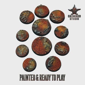 May include: Ten circular miniature bases with a textured, painted finish. The bases feature a reddish-brown and yellow-orange colour palette, with grey rock detailing. The text "PAINTED & READY TO PLAY" is visible at the bottom of the image.