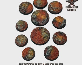 May include: A collection of ten circular, textured bases for miniature figures. The bases are painted with a reddish-brown and yellow-orange color scheme, with gray rock accents. The text "PAINTED & READY TO PLAY" is displayed at the bottom.