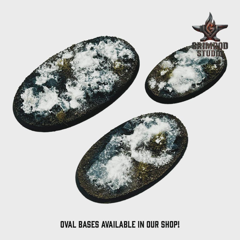 May include: Three oval bases with a textured, snow-covered terrain. The bases are dark brown with patches of green and white, and are designed for miniature figures. The text "OVAL BASES AVAILABLE IN OUR SHOP!" is at the bottom.