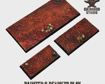 May include: Three rectangular terrain bases with a textured, reddish-brown surface, scattered with small, bone-colored objects. The bases are painted and ready to play, with the text "PAINTED & READY TO PLAY" at the bottom. The Grimrod Studio logo is in the upper right corner.