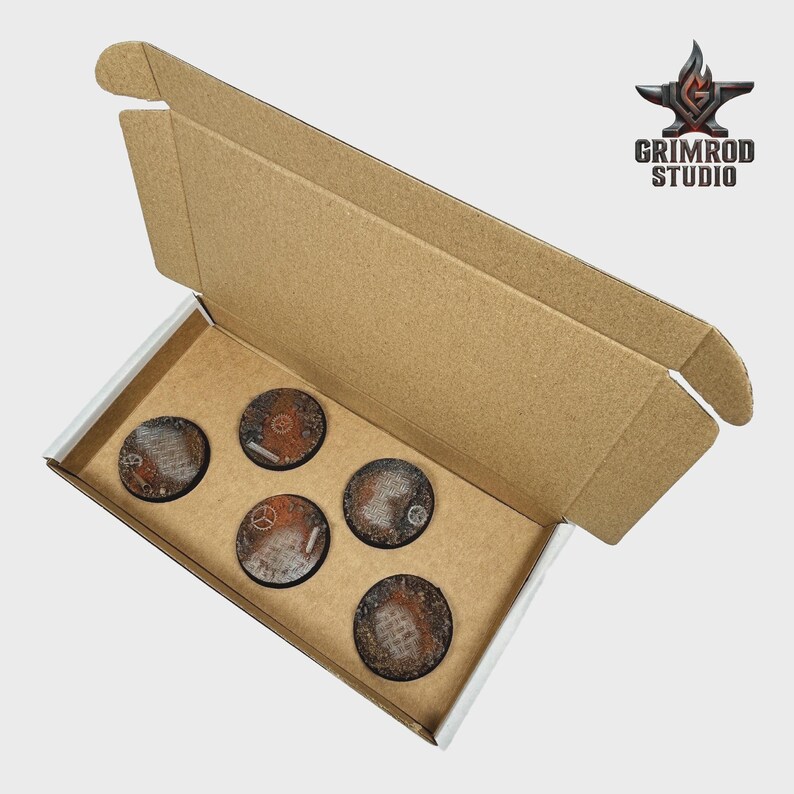 Pu&ograve; includere: Scatola di cartone aperta contenente cinque basi circolari strutturate. Le basi presentano un design industriale arrugginito con accenti metallici. Il logo Grimrod Studio &egrave; visibile in alto a destra.