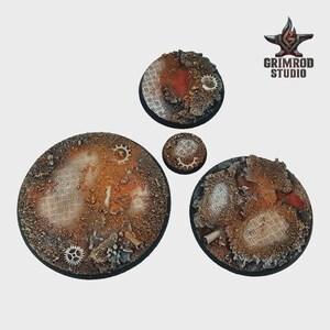 Pu&ograve; includere: Quattro basi circolari con un design industriale strutturato. Le basi presentano un mix di tonalit&agrave; ruggine, grigie e marroni, con ingranaggi e piastre metalliche incorporate. Il logo Grimrod Studio si trova nell'angolo in alto a destra.