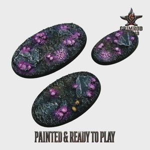 Könnte beinhalten: Drei ovale Miniaturbasen mit einer strukturierten, dunklen Oberfläche. Sie weisen lila, korallenartige Formationen und graue Felsakzente auf. Der Text "PAINTED & READY TO PLAY" ist unten aufgedruckt. Das Grimrod Studio-Logo befindet sich oben rechts.