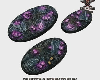 May include: Three oval-shaped miniature bases with a textured, dark surface. The bases feature purple, coral-like formations and gray rock accents. The text "PAINTED & READY TO PLAY" is printed at the bottom. The Grimrod Studio logo is in the upper right corner.