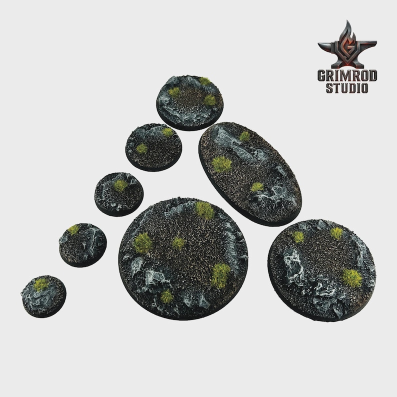 May include: A collection of textured, circular and oval miniature bases. The bases are dark gray with patches of green and white, resembling a rocky terrain. The Grimrod Studio logo is in the upper right corner.
