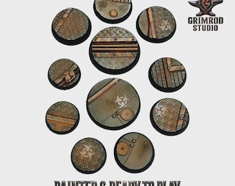 Può includere: Una collezione di dieci basi circolari strutturate con un design industriale metallico. Le basi presentano motivi a piastra diamantata, rivetti e vari accenti metallici. Il testo "PAINTED & READY TO PLAY" è in basso.