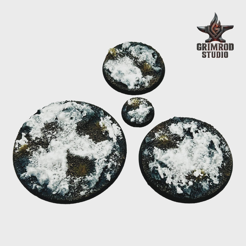 May include: Four circular miniature bases with a snow and terrain design. The bases vary in size and feature a mix of brown, white, and green elements. The Grimrod Studio logo is in the upper right corner.