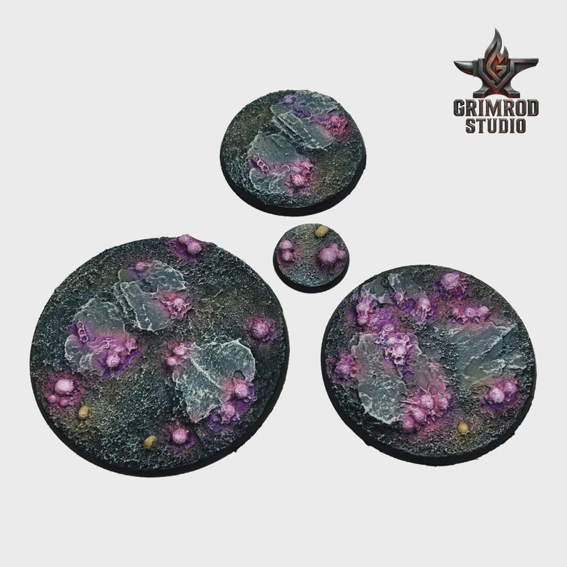 May include: Four textured, circular bases for miniature figures. The bases are painted in dark gray, with purple and pink organic-looking formations and light gray rock-like structures. The Grimrod Studio logo is in the upper right corner.