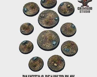 May include: A collection of ten circular, textured bases for miniature figures. The bases are painted with a desert-like terrain, featuring cracked earth, small rocks, and patches of dry grass. The text "PAINTED & READY TO PLAY" is visible.
