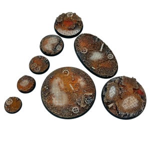 Peut inclure: Ensemble de huit socles miniatures à l'esthétique industrielle. Les socles présentent des textures rouillées, métalliques et bétonnées, avec des engrenages et des grilles. Les formes varient, allant du rond à l'ovale.