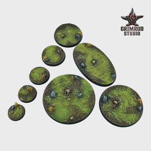 May include: A collection of miniature bases in various shapes, including round and oval. The bases are textured with green grass, small rocks, and patches of dirt. Some bases have small tufts of dried grass. The Grimrod Studio logo is in the upper right corner.