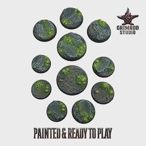 Op de afbeelding: Een verzameling van tien ronde miniatuurbases, beschilderd met een getextureerd, rotsachtig terrein en groene mosvlekken. De bases zijn in een cirkelvormig patroon gerangschikt. De tekst "PAINTED & READY TO PLAY" staat onderaan.