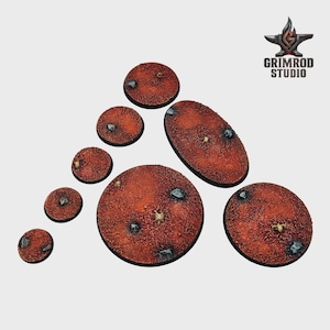 May include: A collection of textured, reddish-brown miniature bases in various shapes and sizes. Each base features embedded stones and small details, with the "Grimrod Studio" logo in the upper right corner.