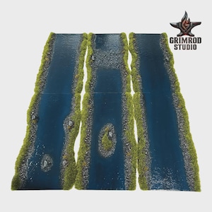 Peut inclure: Trois sections de terrain de rivière pour jeux de plateau, composées d'eau bleu foncé, de berges rocheuses texturées et d'herbe verte floquée. La section centrale comporte un petit îlot, tandis que les sections latérales présentent des rochers.
